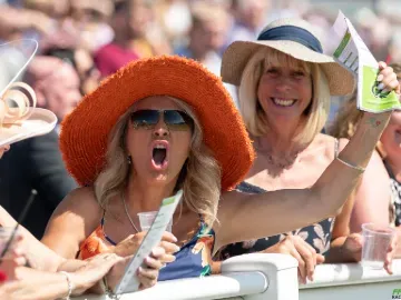 A racegoer at Ffos Las excitedly cheers the race from the track side