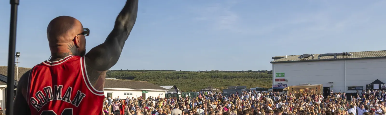 A singer puts his hand in the air performing to the crowd at Ffos Las