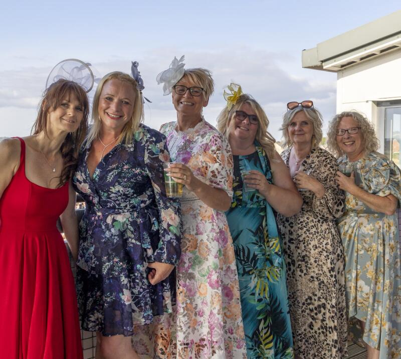 Ladies in beautiful dresses pose for a picture on the hospitality balcony at Ffos Las