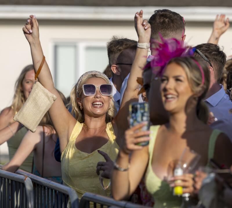 A lady at Ffos Las races throws her arms in the air as she dances to the music