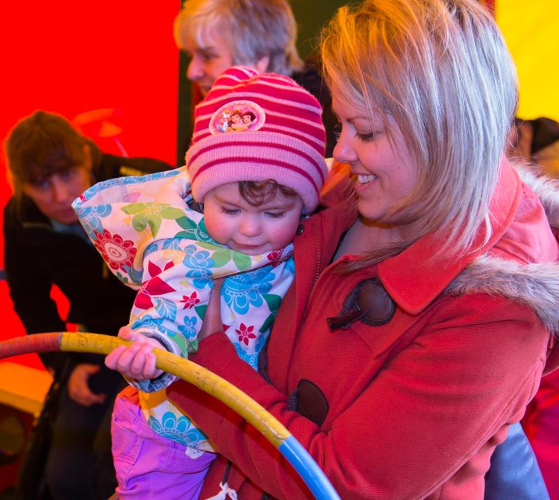 A mother and her young child investigate a hoola hoop