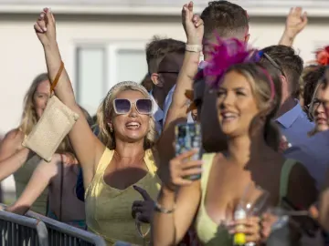A race goer throws her hands in the air at Ffos Las