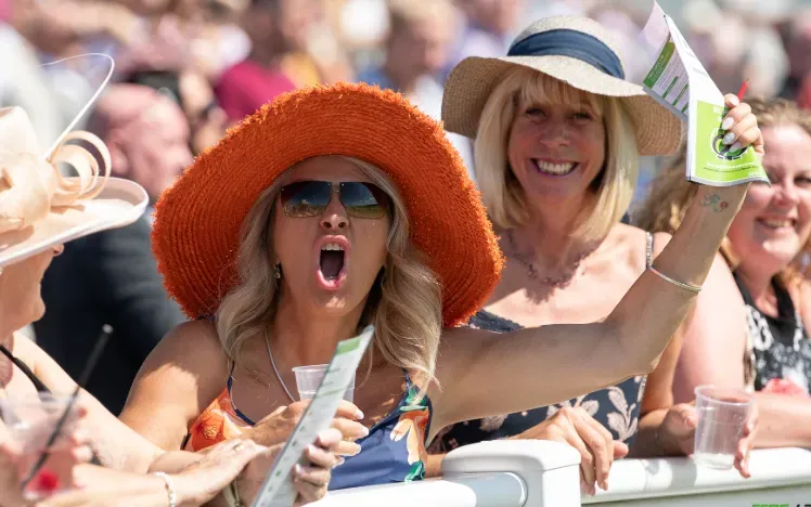 A racegoer at Ffos Las excitedly cheers the race from the track side
