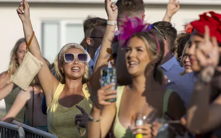 A race goer throws her hands in the air at Ffos Las