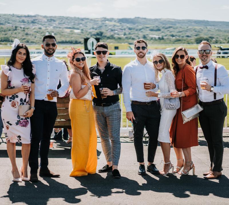 A large group of friends pose in the sun at Ffos Las Races