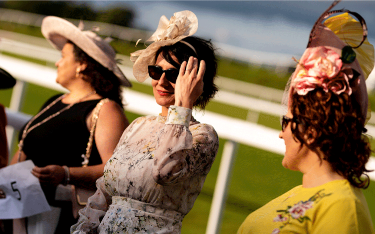 Women smile in the sunshine dressed in their best clothing