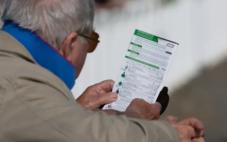 A racegoer studying the racecard at Ffos Las