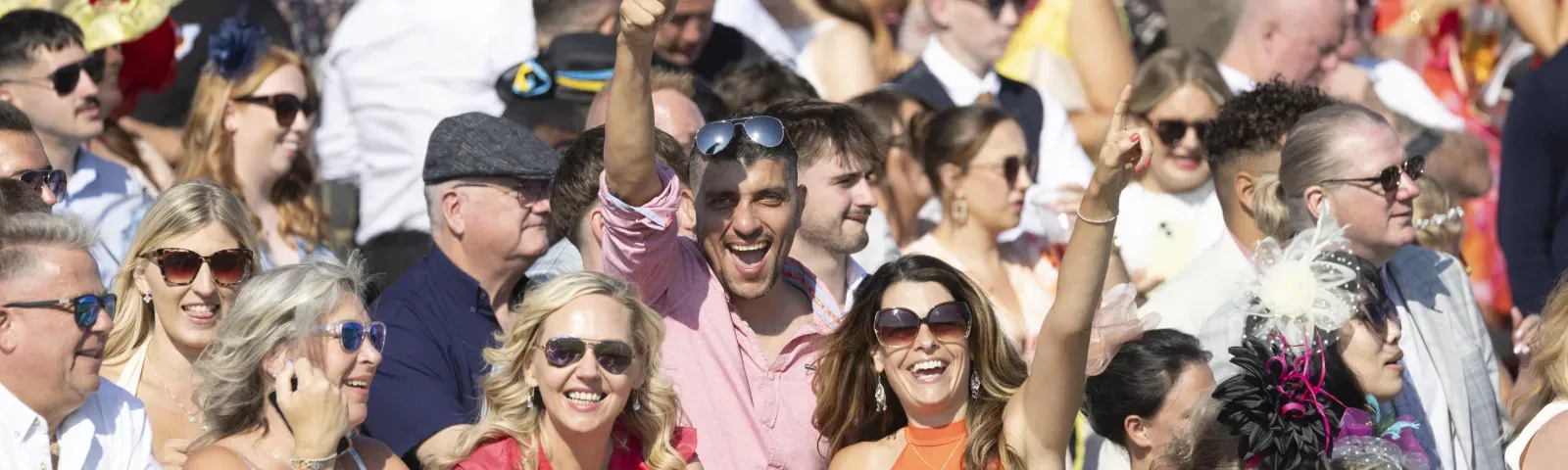 Some of the crowd at Ffos Las throw their hands in the air for the camera