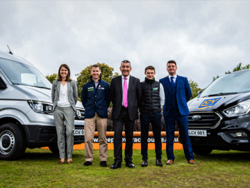 The new sponsors stand in front of vans