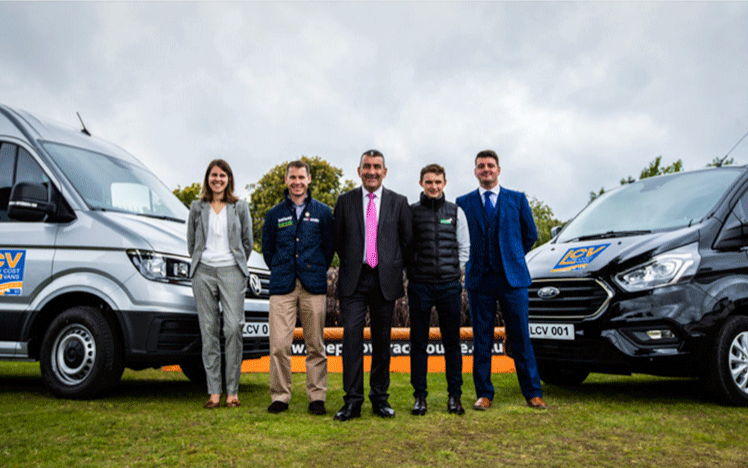 The new sponsors stand in front of vans